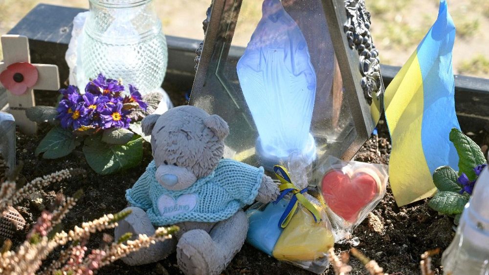 No cemitério militar Lychakiv, em Lviv, flores, vela e urso de pelúcia recordam morte de criança em ataque russo. (Photo by Yuriy Dyachyshyn/AFP)
