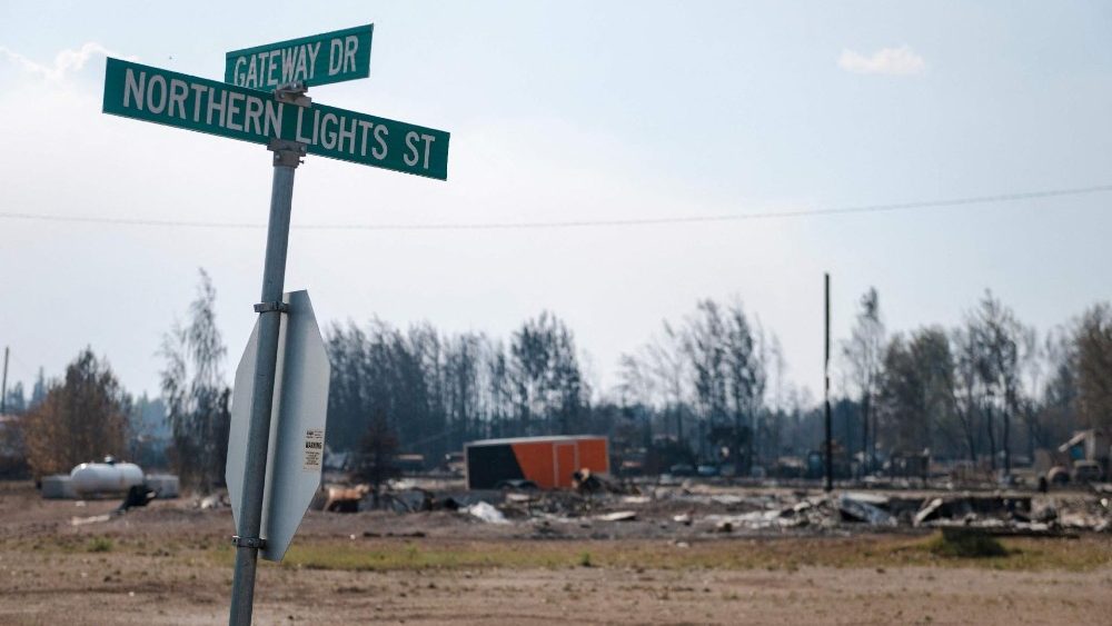 Uma placa de rua é vista em frente a restos carbonizados na beira da estrada ao lado da rodovia em Enterprise, Territórios do Noroeste, Canadá, em 20 de agosto de 2023. (Photo by ANDREJ IVANOV / AFP)