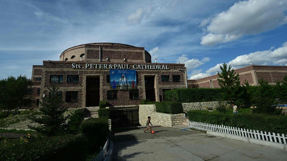 Um menino brinca na frente do Sts. Catedral Católica de Pedro e Paulo adornada com um pôster do Papa Francisco em Ulaanbaatar em 31 de agosto de 2023. O Papa Francisco deve visitar a Mongólia e visitar a capital do país de maioria budista a convite do governo esta semana, tornando-se o primeiro pontífice a pisar lá . (Foto de Pedro PARDO/AFP)