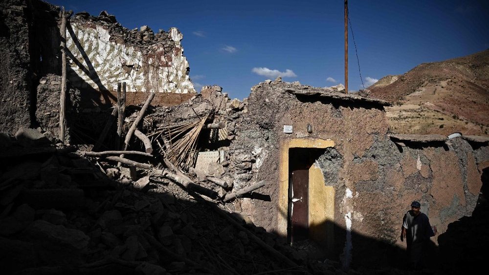 Um sobrevivente do terremoto caminha em frente a casas destruídas na aldeia de Ighermane, perto de Adassil, no centro de Marrocos, em 13 de setembro de 2023. (Photo by Philippe LOPEZ / AFP)