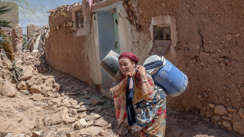 Uma sobrevivente do terremoto carrega pertences recuperados em um vilarejo perto de Amizmiz, no centro de Marrocos, em 13 de setembro de 2023. (Photo by BULENT KILIC / AFP)