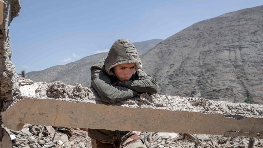 Um jovem sobrevivente do terremoto se apoia em uma viga de cimento entre os escombros de um prédio destruído em um vilarejo perto de Amizmiz, no centro de Marrocos, em 13 de setembro de 2023. (Photo by BULENT KILIC / AFP)