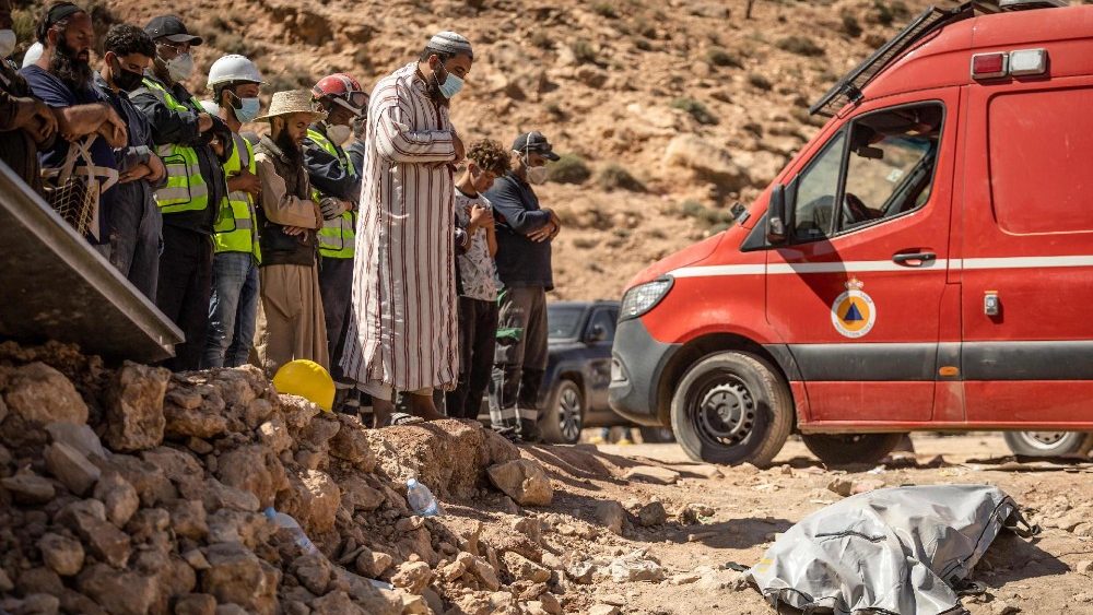 Aldeões e equipes de resgate recitam uma oração em frente ao corpo de um terremoto na aldeia de Imi N'Tala, perto de Amizmiz, em 13 de setembro de 2023. (Photo by FADEL SENNA / AFP)