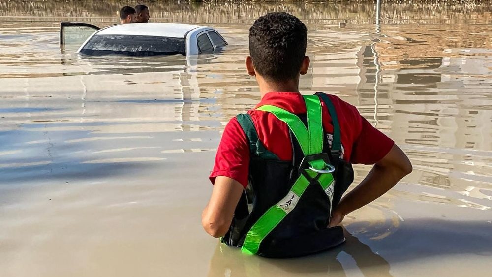 Esta imagem divulgada por conta do Crescente Vermelho Líbio na plataforma X (anteriormente Twitter) em 14 de setembro de 2023, mostra um membro parado em uma área inundada perto de um veículo submerso após as enchentes após a tempestade no Mediterrâneo "Daniel" atingiu a cidade de Derna, no leste da Líbia. (Photo by Libyan Red Crescent / AFP)