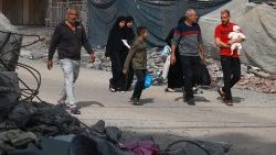 Uma família palestina caminha ao lado de escombros em Rafah, no sul da Faixa de Gaza. 