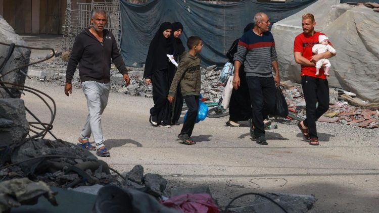 Uma família palestina caminha ao lado de escombros em Rafah, no sul da Faixa de Gaza. 