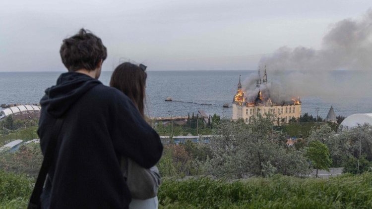 Um casal olha para um prédio em chamas danificado por um ataque de mísseis em Odesa, em 29 de abril de 2024, em meio à invasão russa da Ucrânia. Um ataque com mísseis russo em 29 de abril de 2024 matou pelo menos duas pessoas e feriu oito na cidade portuária de Odesa, no sul da Ucrânia, disse o governador local. (Foto de Oleksandr GIMANOV/AFP)