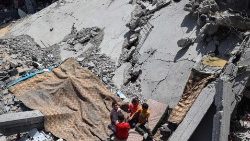 Palestinian children sit on a mattress on the rubble of a building destroyed by an Israeli strike