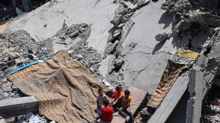 Palestinian children sit on a mattress on the rubble of a building destroyed by an Israeli strike
