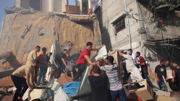 Alcuni palestinesi cercano sopravvissuti sotto le macerie al campo profughi di al-Bureij