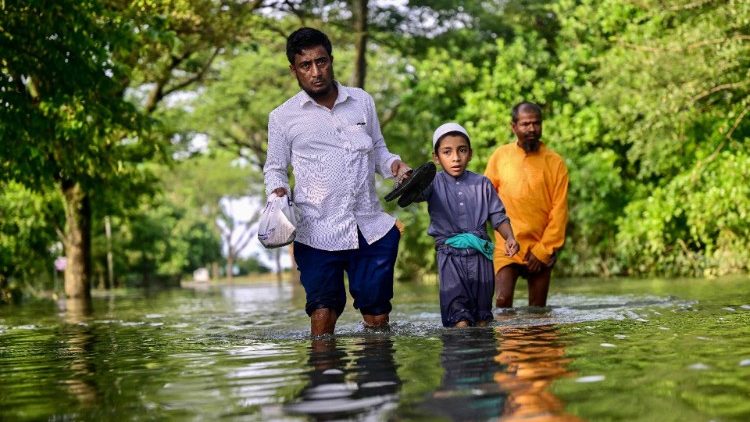 Pessoas atravessam águas inundadas após fortes chuvas em Sylhet