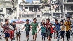 Crianças palestinas em meio a prédios destruídos em Khan Yunis, no sul da faixa de Gaza, em 8 de julho de 2024, em meio ao conflito entre Israel e Hamas. AFP/Bahsar Taleb