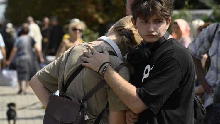 Pessoas se abraçam enquanto esperam para embarcar em um trem de evacuação em um local não revelado na região de Donetsk em 26 de agosto de 2024, em meio à invasão russa na Ucrânia. (Foto de Genya SAVILOV / AFP)