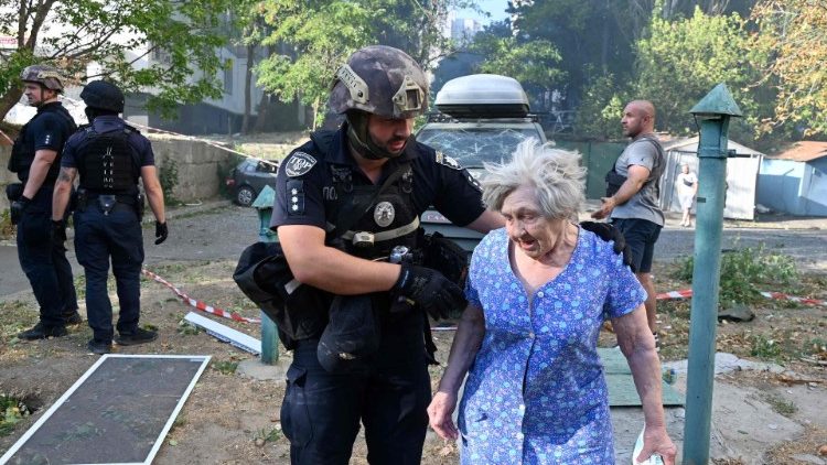 Um policial ucraniano ajuda uma idosa a deixar o local de um ataque com mísseis em Kharkiv em 15 de setembro de 2024, em meio à invasão russa da Ucrânia. (Foto de SERGEY BOBOK / AFP)