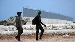 Haitian citizens walk past the border wall being built in the Dominican Republic-Haiti border