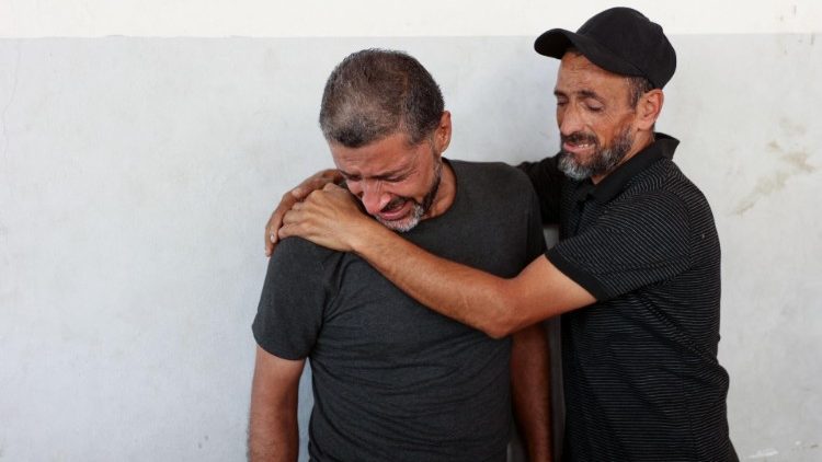 Men mourn relative in the courtyard of the al-Maamadani hospital where the victims of an Israeli stirke that hit a UN-School turned refuge in Al-Shati refugee camp in Gaza were transported 