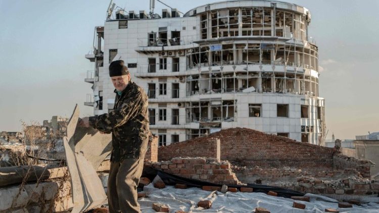 Mykola Hrishyn, 71, remove os destroços do telhado para que não caiam, no topo de um prédio destruído onde fica seu apartamento, em Kharkiv, em 26 de outubro de 2024, em meio à invasão russa na Ucrânia. Em março de 2022, um míssil russo atingiu o prédio onde a família Hrishyn morava, danificando gravemente seu apartamento e forçando a família a procurar outro lugar para morar. No verão de 2022, eles se mudaram para o porão do mesmo prédio residencial onde ficava seu apartamento e desde então estão morando lá. (Foto de Ivan SAMOILOV / AFP)