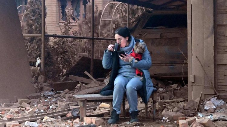 Uma mulher segurando seu cachorro bebe café entre os destroços após um ataque com mísseis em Kharkiv em 29 de outubro de 2024. Ataques russos em um bairro residencial da segunda maior cidade da Ucrânia, Kharkiv, mataram pelo menos quatro pessoas em 29 de outubro de 2024, disse o prefeito. (Foto de SERGEY BOBOK / AFP)