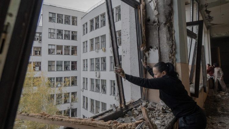 Uma mulher limpa escombros dentro do edifício Derzhprom danificado, um arranha-céu histórico soviético, após um ataque de mísseis em Kharkiv em 29 de outubro de 2024. (Foto de Ivan SAMOILOV / AFP)