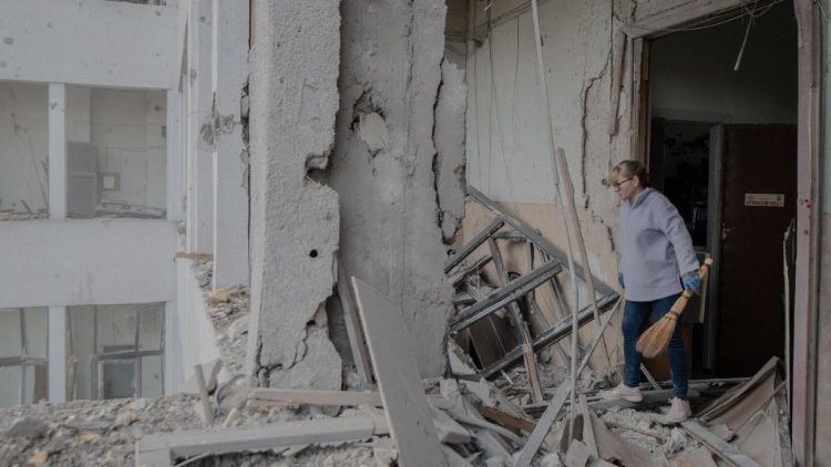 Uma mulher limpa escombros dentro do edifício Derzhprom danificado, um arranha-céu histórico soviético, após um ataque de mísseis em Kharkiv em 29 de outubro de 2024. (Foto de Ivan SAMOILOV / AFP)
