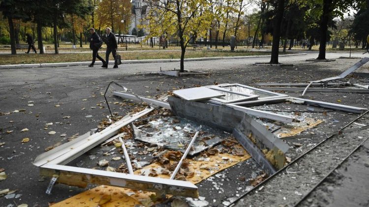 Moradores locais passam por janelas quebradas no chão perto de um prédio residencial danificado, na cidade de Pokrovsk, região de Donetsk, em 29 de outubro de 2024, em meio à invasão russa na Ucrânia. (Foto de Genya SAVILOV / AFP)