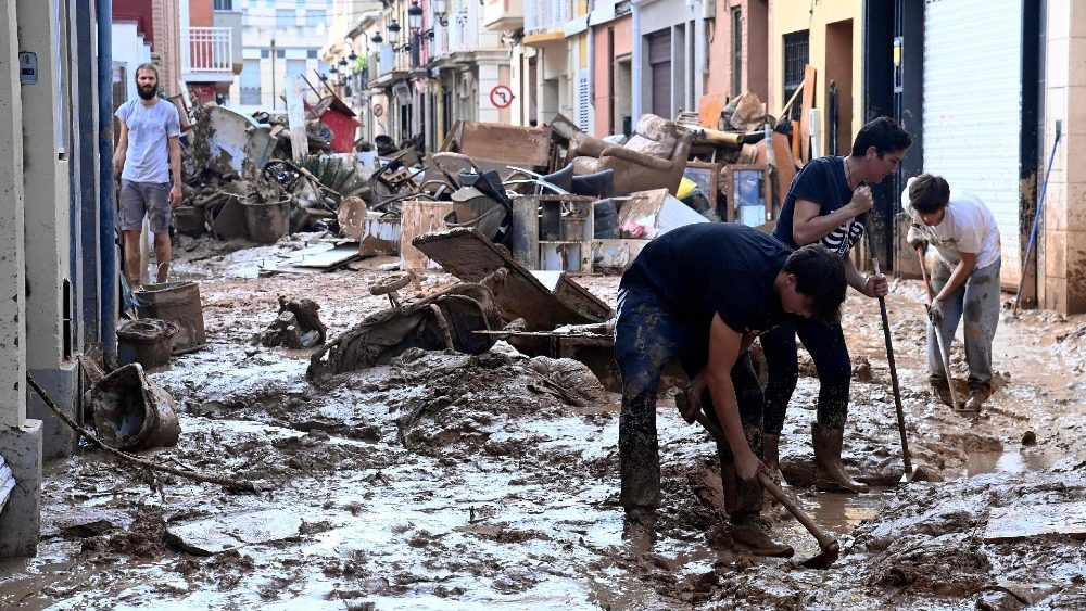 Pessoas tentam limpar as ruas tomadas por destroços e pela lama em Palporta, Valência. (Photo by Jose Jordan/AFP)