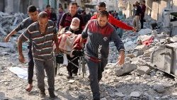 Uomini palestinesi trasportano un anziano in sedia a rotelle tra le macerie del campo profughi di Jabalya, nel nord della Striscia di Gaza (Afp)