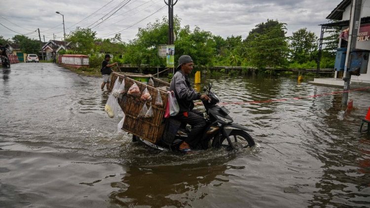 A food vendor rides through the floodwaters in Tempuran village in Mojokerto, East Java on December 9
