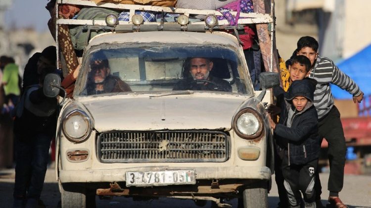 Crianças palestinas ajudam a empurrar um carro enquanto as pessoas deixam suas casas após receberem ordens de evacuação no campo de refugiados de Bureij, centro da Faixa de Gaza (AFP)
