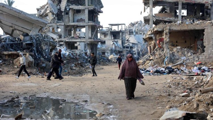 Palestinians walk amid the destruction of a neighbourhood in Gaza City