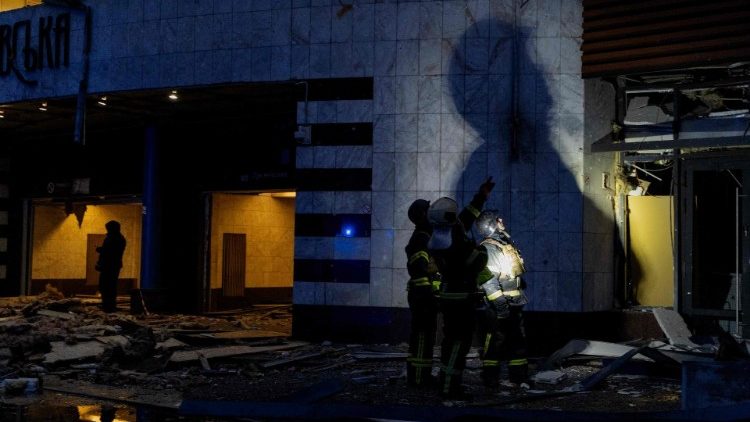 Bombeiros projetam uma sombra gigante em uma parede enquanto inspecionam os danos a um prédio perto de uma estação de metrô após um ataque de foguete em Kiev em 18 de janeiro de 2025, em meio à invasão russa da Ucrânia. (Foto de Tetiana DZHAFAROVA / AFP)