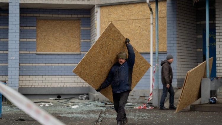 Um homem carrega uma placa para cobrir janelas danificadas após ataques aéreos russos na região de Kiev em 24 de janeiro de 2025, em meio à invasão russa da Ucrânia. (Foto de Tetiana DZHAFAROVA / AFP)