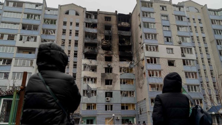 Pessoas olham para um edifício residencial danificado após ataques aéreos russos na região de Kiev em 24 de janeiro de 2025, em meio à invasão russa da Ucrânia. (Foto de Tetiana DZHAFAROVA / AFP)