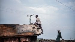 Children play on the charred remains of UN armoured vehicles  in eastern DR Congo as an uneasy calm held after regional peace summit