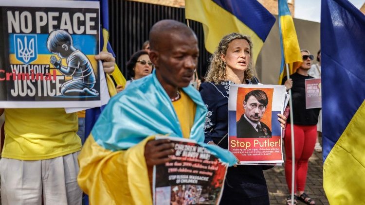 Membros do #StandWithUkraine seguram cartazes durante uma manifestação do lado de fora do Consulado Russo em Pretória em 24 de fevereiro de 2025 no terceiro aniversário da invasão da Ucrânia pela Rússia em 2022. A África do Sul disse em 21 de fevereiro de 2025 que as negociações para acabar com a guerra de quase três anos da Rússia na Ucrânia devem envolver todas as partes e o presidente ucraniano Volodymyr Zelensky era esperado em uma visita de estado em breve para discussões. O presidente Cyril Ramaphosa convidou Zelensky para negociações após fortes críticas às ações da Rússia e dos Estados Unidos para negociar o fim da guerra por meio de um processo para o qual nem a Ucrânia nem seus aliados europeus foram convidados. (Foto de Marco LONGARI / AFP)