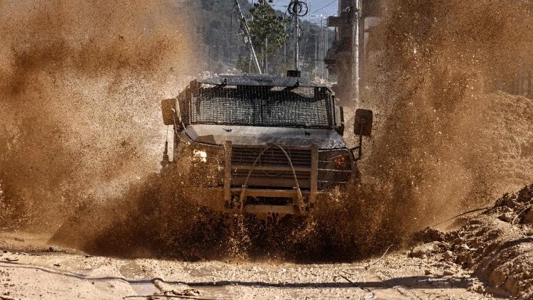 Forças israelenses dirigem em uma estrada destruída no campo de refugiados palestinos de Nur Shams, perto de Tulkarem, após supostamente emitirem notificações de demolição de várias casas em meio a uma ofensiva de semanas na Cisjordânia ocupada em 26 de fevereiro de 2025. (Foto de Zain JAAFAR / AFP)