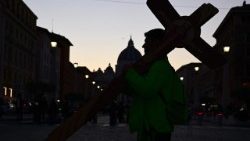 A pilgrim carries a wooden cross towards St Peter's Square