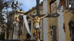 Kruzifix vor einer zerbombten Kirche in der Ukraine