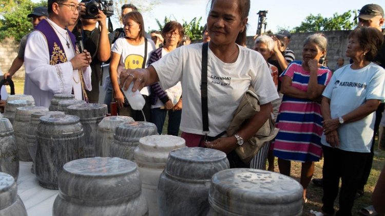 A woman blesses an urn containing the ashes of victims killed during former Philippine president Rodrigo Duterte's war on drugs