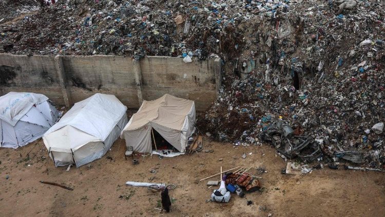 A displaced Palestinian woman stands outside tents in the Yarmuk area of Gaza City