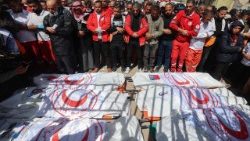 Members of the Palestine Red Crescent and other emergency services carry bodies of  fellow rescuers killed by Israeli forces