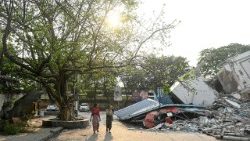 Residenti davanti a un edificio crollato a Mandalay, in Myanmar (Afp)