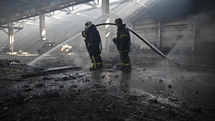 Bombeiros ucranianos trabalham dentro da oficina de uma empresa privada após um ataque de drone russo em Kharkiv, em 22 de abril de 2025, em meio à invasão russa da Ucrânia. (Foto de SERGEY BOBOK / AFP)