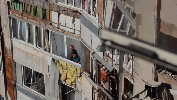 Moradores observam pelas janelas quebradas de um prédio residencial danificado após um ataque de drones em Odessa, em 1º de maio de 2025, em meio à invasão russa da Ucrânia. Um ataque de drones russos durante a noite matou pelo menos duas pessoas e feriu outras 15 em uma área residencial de Odessa, informaram os serviços de emergência ucranianos na manhã de 1º de maio de 2025. (Foto de Oleksandr GIMANOV / AFP)