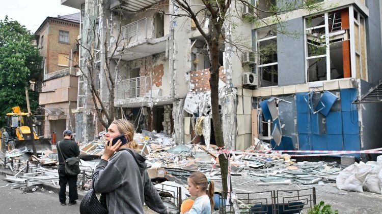 In Kyiv, people walk past a multistory residential building damaged by Russian attacks