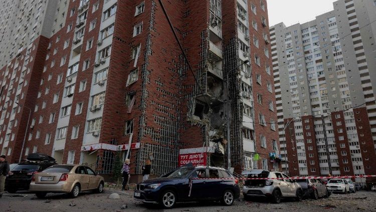 Pessoas ao lado de um prédio residencial danificado após ataques de drones à capital da Ucrânia, Kiev, em 10 de junho de 2025, em meio à invasão russa na Ucrânia. A Rússia realizou ataques "massivos" com drones contra a capital da Ucrânia, Kiev, e a cidade portuária de Odessa na manhã de 10 de junho, matando uma pessoa e atingindo uma maternidade, disseram autoridades ucranianas, que pediram novas sanções. (Foto de Tetiana DZHAFAROVA / AFP)