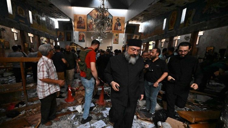 Sacerdote caminha chorando entre os destroços,  enquanto pessoas e equipes de resgate inspecionam os danos no local de um suposto ataque suicida na igreja de Santo Elias, na área de Dwelaa, em Damasco, em 22 de junho de 2025. A mídia estatal síria noticiou um ataque suicida contra uma igreja de Damasco em 22 de junho, que deixou vítimas. Correspondentes da AFP no local viram socorristas transportando pessoas do local. (Foto de LOUAI BESHARA / AFP)