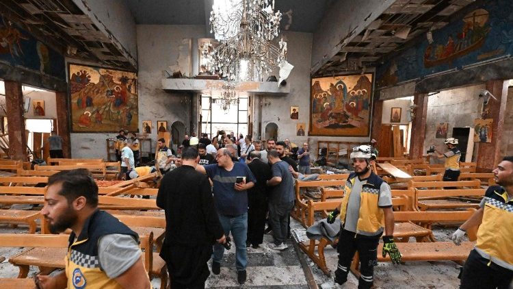 Pessoas e equipes de resgate inspecionam os danos no local de um suposto ataque suicida na igreja de Santo Elias, na área de Dwelaa, em Damasco, em 22 de junho de 2025. A mídia estatal síria noticiou um ataque suicida contra uma igreja de Damasco em 22 de junho, que deixou vítimas. Correspondentes da AFP no local viram socorristas transportando pessoas do local. (Foto de LOUAI BESHARA / AFP)
