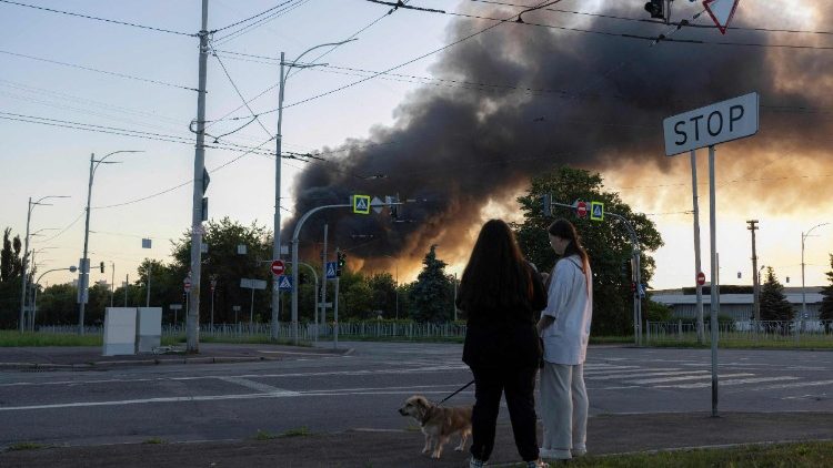 Mulheres passeiam com cachorro enquanto fumaça sobe sobre Kiev após ataques em massa de drones e mísseis russos contra a capital ucraniana em 4 de julho de 2025, em meio à invasão russa da Ucrânia. A Ucrânia afirmou que a Rússia lançou 550 drones e mísseis contra o país devastado pela guerra durante a noite, enquanto o Kremlin intensifica os ataques aéreos e as negociações de paz lideradas pelos EUA estagnam. A Força Aérea Ucraniana afirmou que Moscou lançou 539 drones e 11 mísseis, acrescentando que unidades de defesa aérea abateram 268 drones e dois mísseis. (Foto de OLEKSII FILIPPOV / AFP)