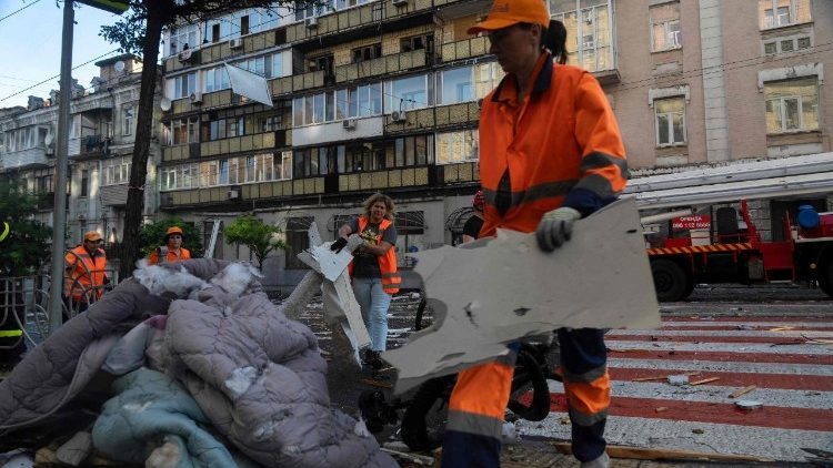 Trabalhadores removem escombros e detritos das ruas após um grande ataque russo durante a noite em Kiev, em 10 de julho de 2025, em meio à invasão russa da Ucrânia. O presidente ucraniano instou os aliados a acelerarem a imposição de novas sanções à Rússia em 10 de julho, após Moscou ter lançado um ataque noturno de horas contra a Ucrânia com centenas de drones e mísseis. (Foto de OLEKSII FILIPPOV / AFP)